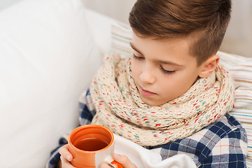 Image showing ill boy with flu in scarf drinking tea at home