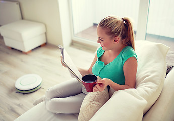 Image showing happy woman reading magazine with tea cup at home