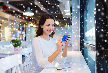 Image showing smiling woman with smartphone at cafe