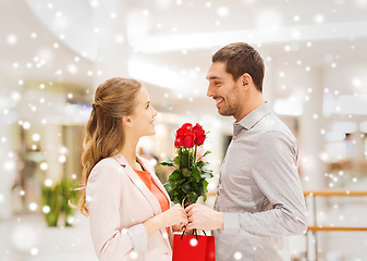 Image showing man giving woman red roses and present in mall