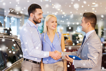 Image showing happy couple with car dealer in auto show or salon