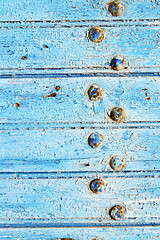 Image showing stripped paint in  blue     door and rusty nail