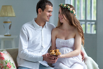 Image showing Cheerful young couple with baby shoes sitting at home