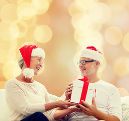 Image showing happy senior couple with gift box at home