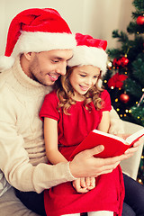 Image showing smiling father and daughter reading book