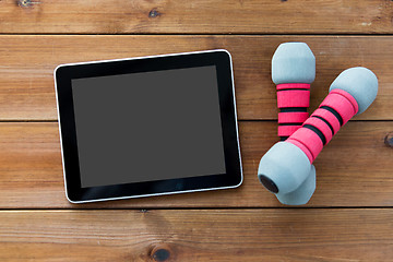 Image showing close up of dumbbells and tablet pc on wood