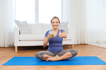 Image showing woman with smoothie showing thumbs up at home