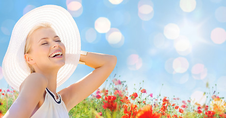 Image showing smiling young woman in straw hat on poppy field