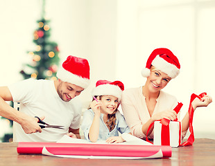 Image showing smiling family in santa helper hats with gift box