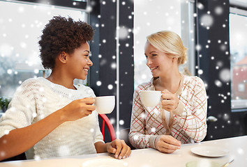 Image showing happy young women drinking tea or coffee at cafe