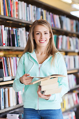 Image showing happy student girl or woman with book in library