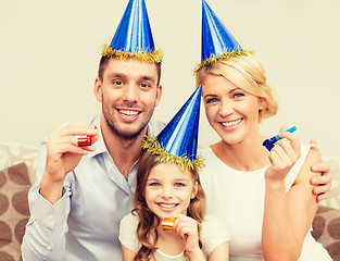 Image showing smiling family in blue hats blowing favor horns