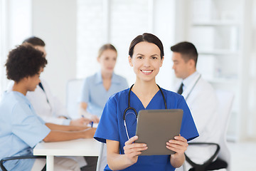 Image showing happy doctor with tablet pc over team at clinic