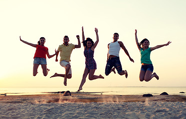 Image showing smiling friends dancing and jumping on beach