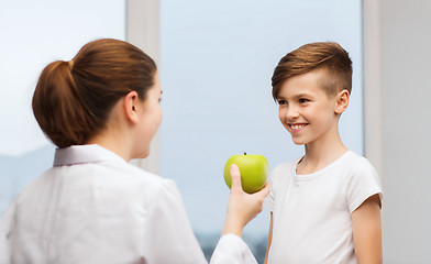 Image showing doctor with green apple and happy boy in clinic