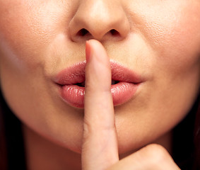 Image showing close up of young woman holding finger on lips