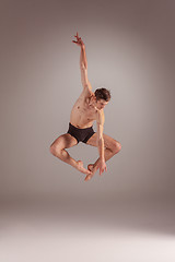 Image showing The young attractive modern ballet dancer jumping on gray background