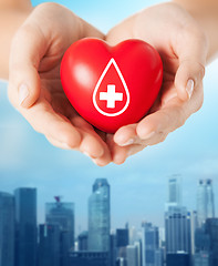 Image showing female hands holding red heart with donor sign