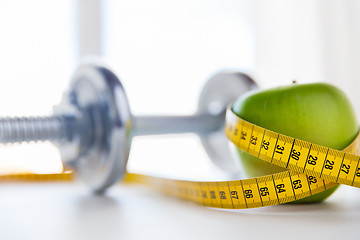 Image showing close up of dumbbell and apple with measuring tape