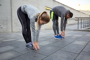 Image showing couple stretching and bending forward on street