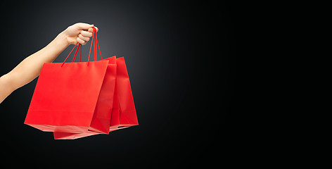Image showing close up of hand holding red shopping bags