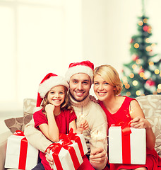 Image showing smiling family holding gift boxes and sparkles