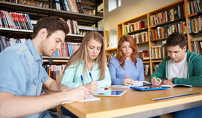 Image showing happy students writing to notebooks in library