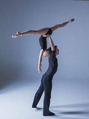 Image showing two young modern ballet dancers on blue studio background 