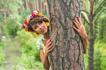 Image showing Attractive woman with flower wreath behind pine