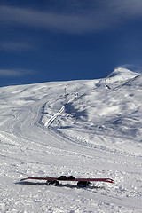 Image showing Snowboard in snow on ski slope at sun windy day