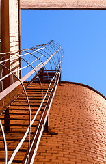 Image showing Industrial ladder, blue sky and brick walls of the building