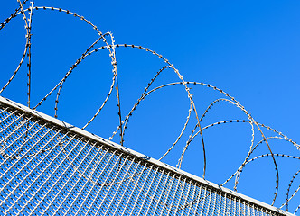 Image showing Fence with a barbed wire against the blue sky. 