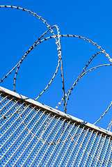 Image showing Fence with a barbed wire against the blue sky. 