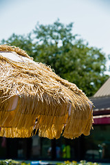 Image showing Straw beach umbrella on blue sky background