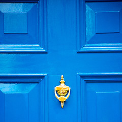 Image showing  blue handle in london antique brown door  rusty  brass nail and