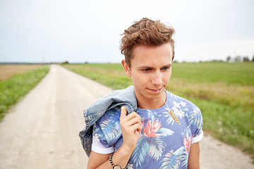 Image showing sad young hippie man walking along country road