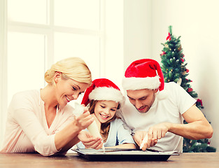 Image showing happy family in santa helper hats cooking