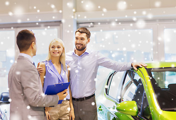 Image showing happy couple with car dealer in auto show or salon