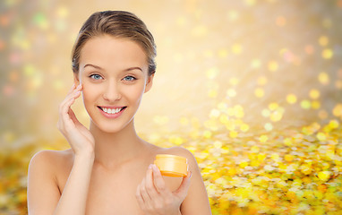 Image showing happy young woman applying cream to her face