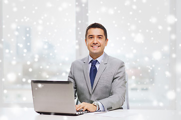 Image showing smiling businessman with laptop and papers
