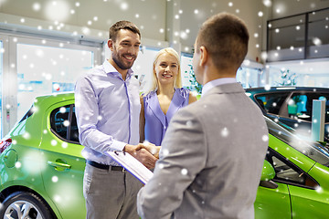 Image showing happy couple with car dealer in auto show or salon