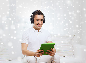 Image showing smiling man with tablet pc and headphones at home