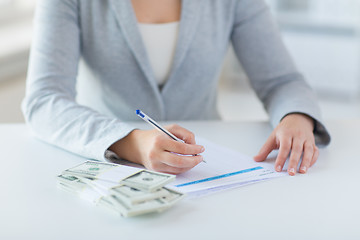 Image showing close up of hands with money filling tax form