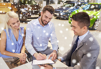 Image showing happy couple with car dealer in auto show or salon