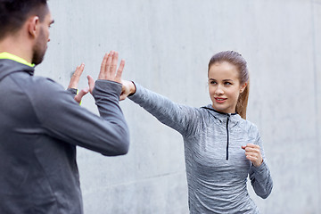 Image showing happy woman with coach working out strike outdoors