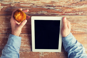 Image showing close up of male hands with tablet pc and muffin