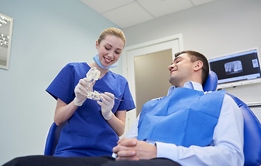 Image showing happy dentist showing jaw layout to male patient