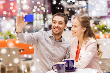 Image showing happy couple with smartphone taking selfie in mall