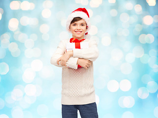 Image showing smiling happy boy in santa hat with gift box