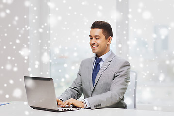 Image showing happy businessman working with laptop in office